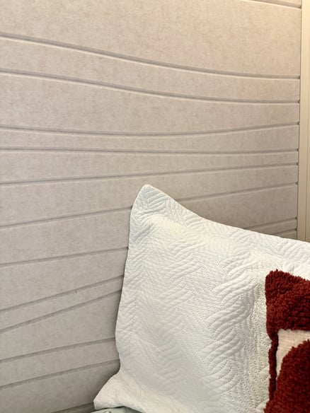 Béžový obklad stěny s bílým polštářem v interiéru ložnice.